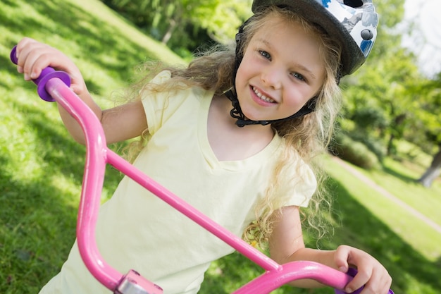 Bambina in bicicletta al parco estivo