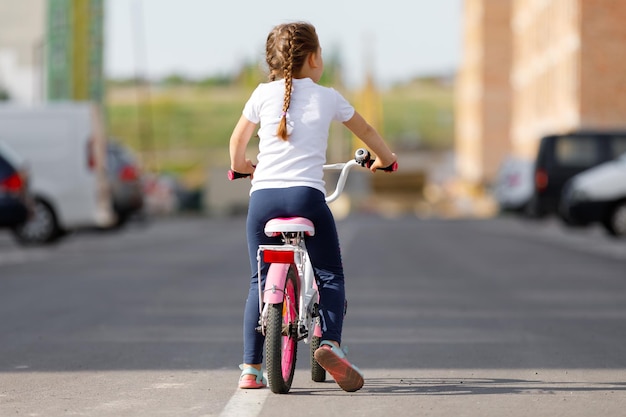 Bambina in bicicletta nel parco estivo in bicicletta all'aperto