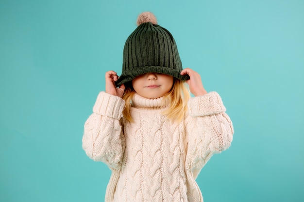 bambina in cappello e maglione di inverno sull'azzurro