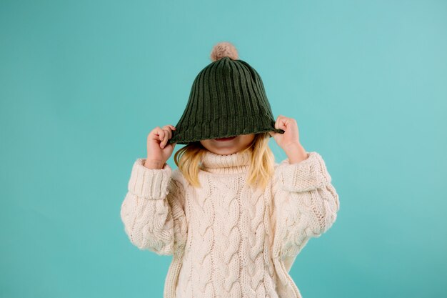 bambina in cappello e maglione di inverno sull'azzurro
