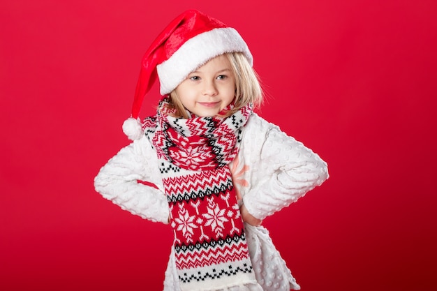 Bambina in cappello e sciarpa di Santa su rosso