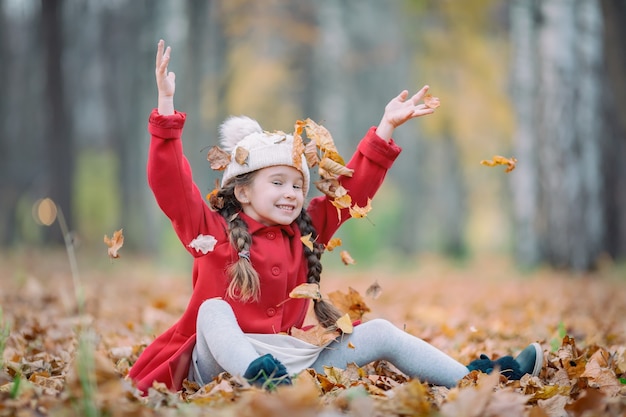 Bambina in cappotto rosso con foglie d'autunno