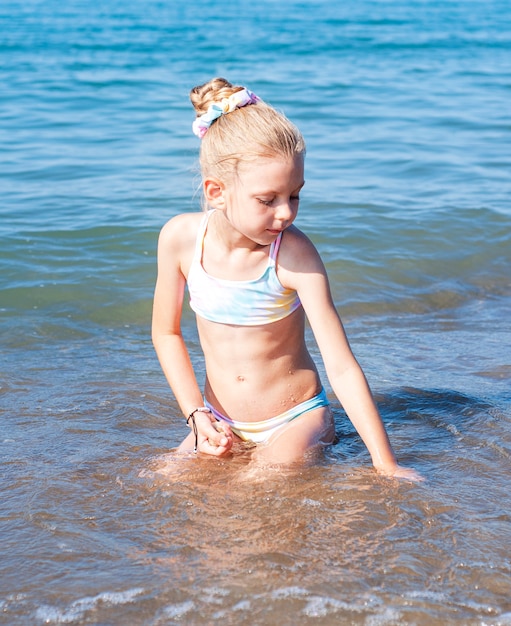 Bambina in costume da bagno che gioca sulla spiaggia in riva al mare