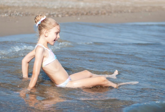 Bambina in costume da bagno che gioca sulla spiaggia in riva al mare