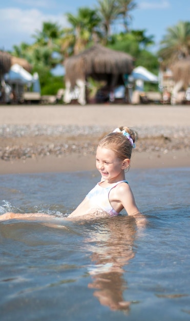 Bambina in costume da bagno che gioca sulla spiaggia in riva al mare