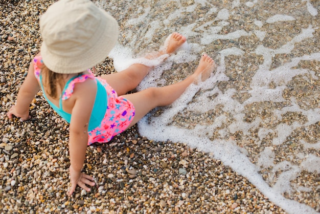 Bambina in costume da bagno che spruzza le gambe nel mare