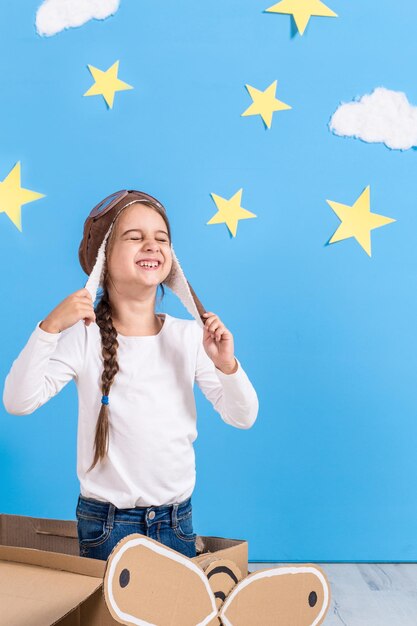 Bambina in costume da pilota sta giocando e sogna di volare sopra le nuvole.