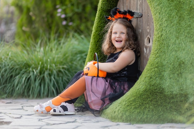 bambina in costume da strega per Halloween passeggiate nel parco in un cesto di caramelle