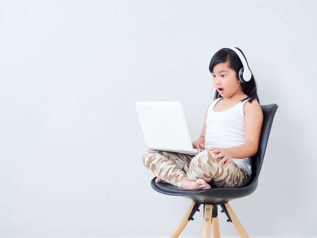 Bambina in cuffia con il computer portatile.