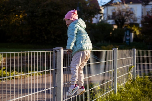 Bambina in età prescolare scavalca la recinzione di ferro nel parco