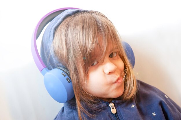 Bambina in felpa casual ascolta il suono della musica con una smorfia di piacere sul suo bel viso giovane Ragazza ribelle e cool Cuffie wireless Moderne tecnologie lifestyle concetto di svago