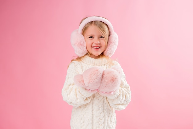 bambina in guanti rosa e cuffie su un muro rosa