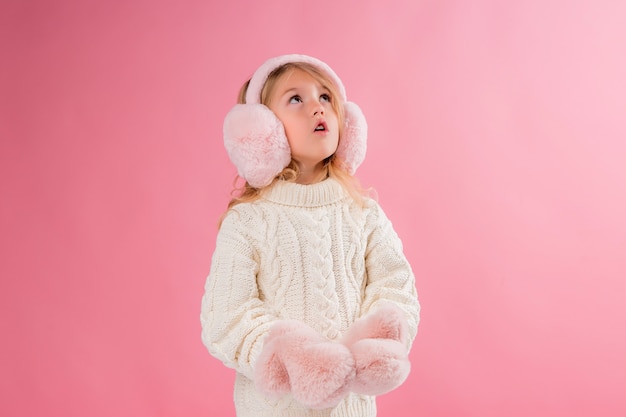 bambina in guanti rosa e cuffie su un muro rosa