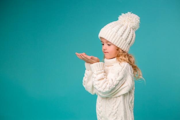 bambina in inverno bianco cappello lavorato a maglia e maglione su blu