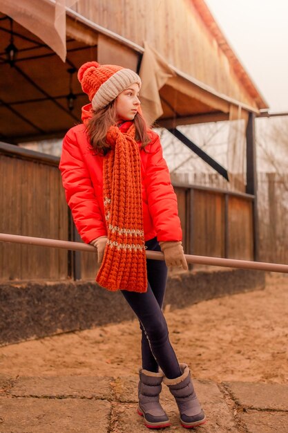 Bambina in inverno con una giacca arancione e un cappello arancione con una sciarpa.