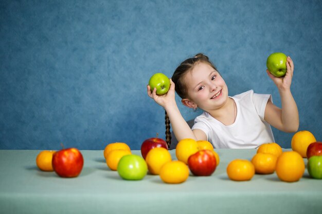 Bambina in maglietta bianca gioca e posa con la frutta