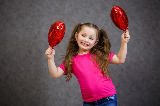 Bambina in maglietta rosa gioca con i palloncini