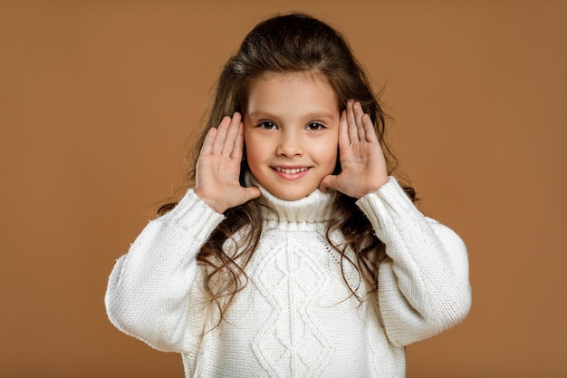 Bambina in maglione bianco che guarda alla macchina fotografica