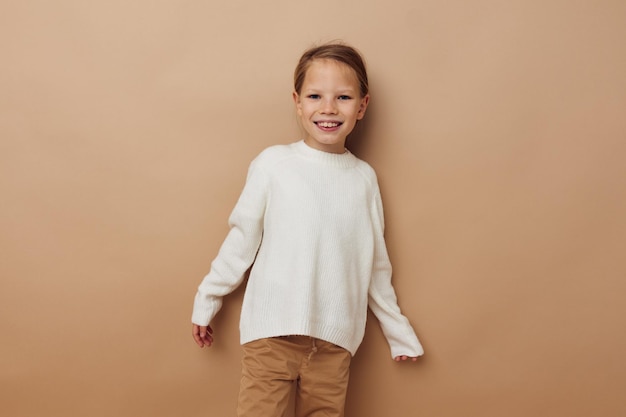 Bambina in maglione bianco in posa gesti di mano sfondo beige