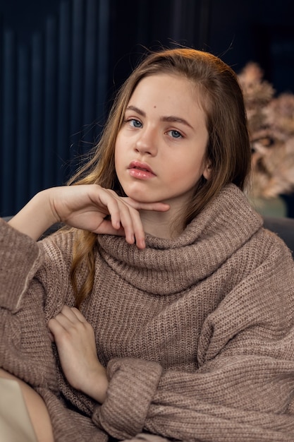 Bambina in maglione marrone, bambina sveglia in vestiti di autunno. Ritratto di una bella bambina sorridente con i capelli lunghi.