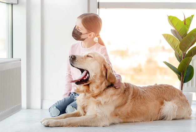 Bambina in maschera con cane golden retriever