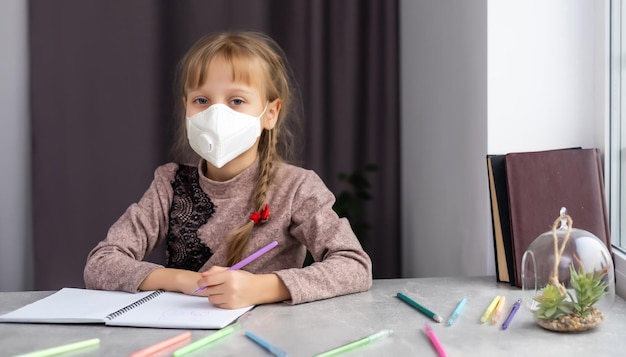 bambina in maschera medica che studia a casa. epidemico pandemico.