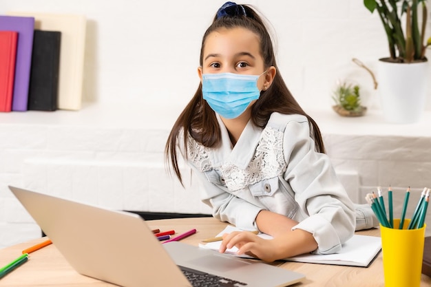 bambina in maschera medica che studia a casa. epidemico pandemico.