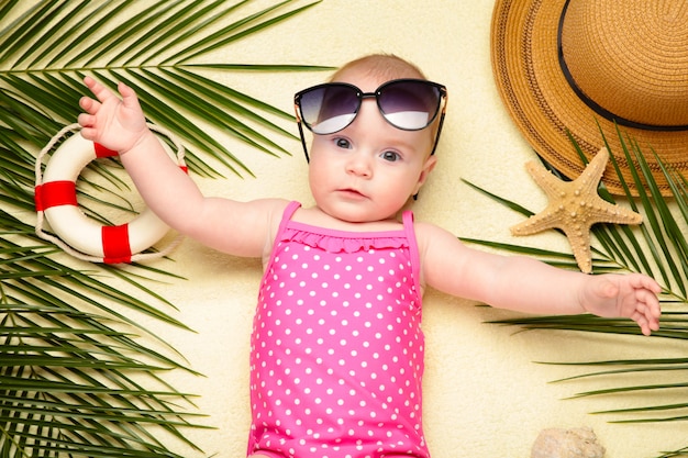 Bambina in occhiali da sole con accessori da spiaggia. Feste in mare con il bambino, concetto di estate