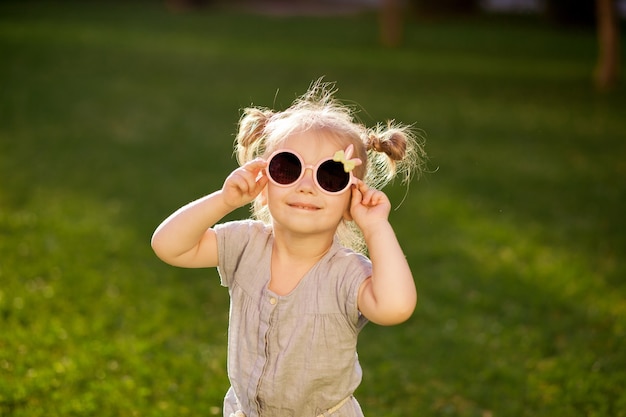 Bambina in occhiali da sole in posa nel parco