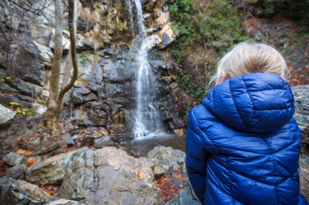 Bambina in piedi davanti alla cascata.