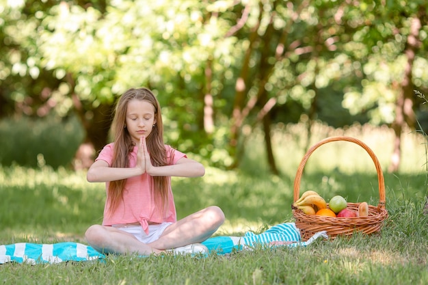 Bambina in posizione yoga nel parco,