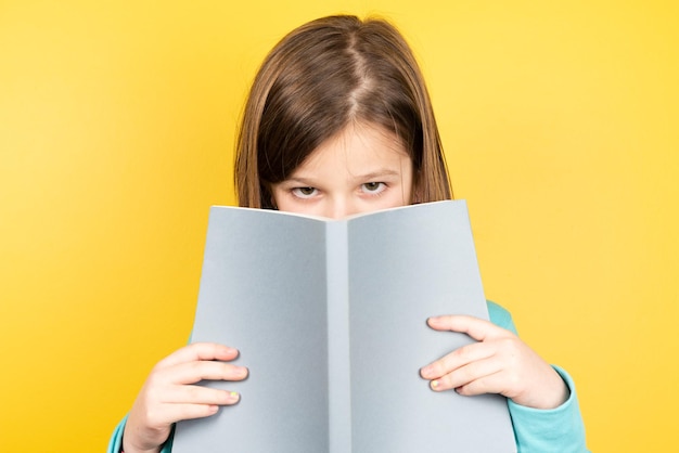 Bambina in possesso di un libro e guardando la telecamera.