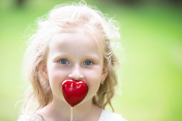 Bambina in possesso di un piccolo cuore rosso Bambino con un cuore giocattolo