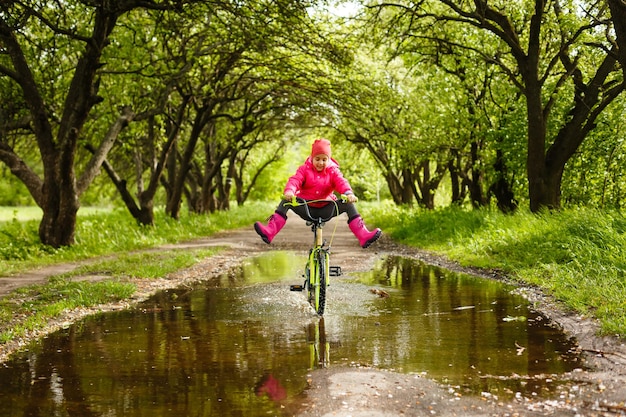 bambina in sella alla bici nella pozza d'acqua