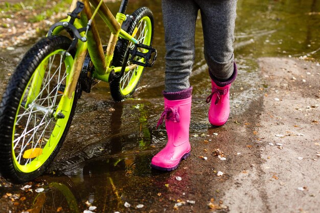 bambina in sella alla bici nella pozza d'acqua