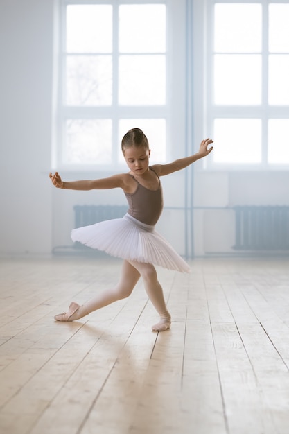 Bambina in tutu che esegue danza classica da sola nella scuola di danza