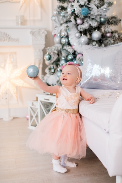 Bambina in un bel vestito vicino all'albero di Natale