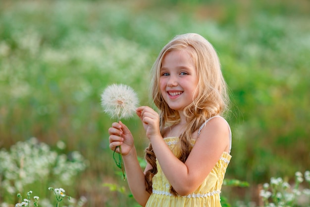 Bambina in un campo con un dente di leone che cammina in estate