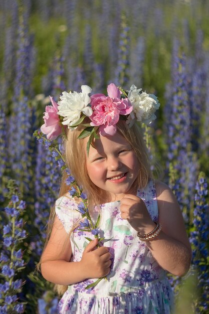 Bambina in un campo di fiori in una soleggiata giornata estiva durante le vacanze estive. Una ragazza con i capelli lunghi sorride e ride.