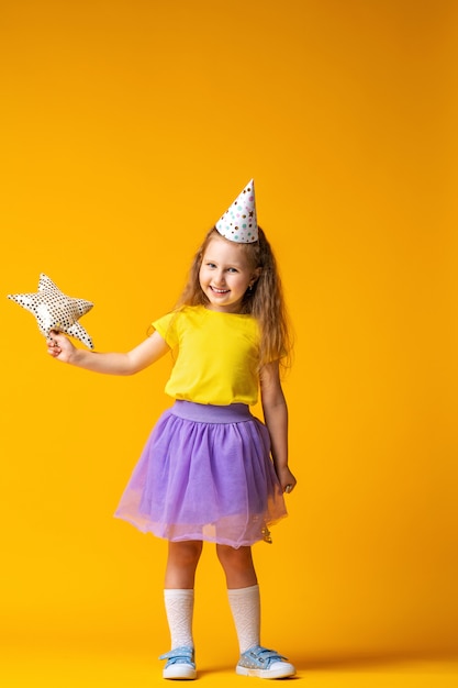 Bambina in un cappello da festa con un palloncino