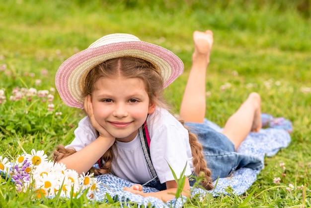 Bambina in un cappello di paglia che riposa in un prato