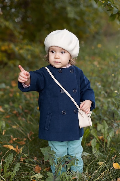 Bambina in un cappotto rosso in autunno tenendo le foglie
