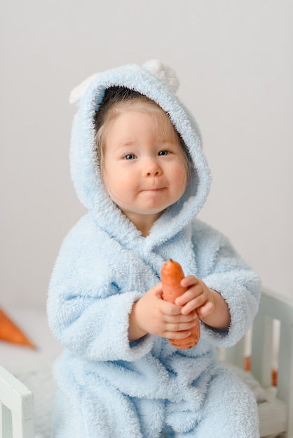 Bambina in un costume da coniglio che mangia le carote.