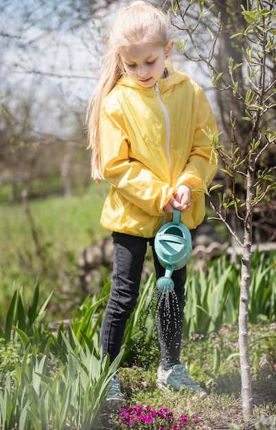 Bambina in un giardino con annaffiatoio verde