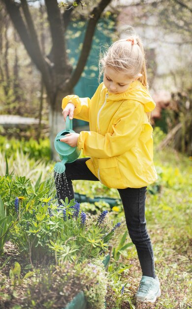 Bambina in un giardino con annaffiatoio verde