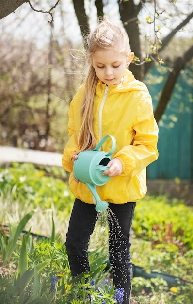 Bambina in un giardino con annaffiatoio verde