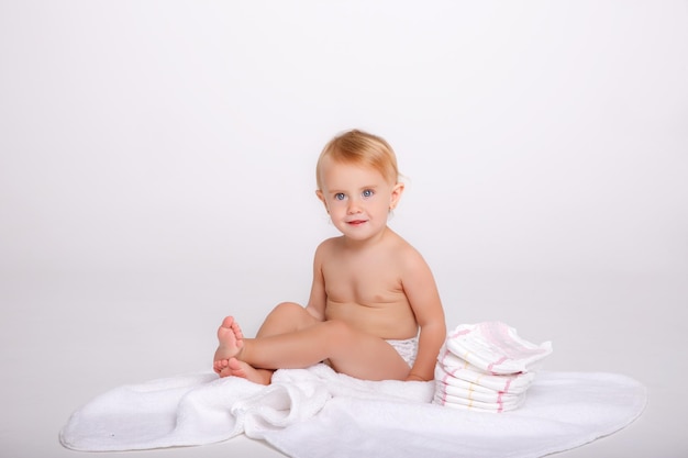 bambina in un pannolino con una pila di pannolini su sfondo bianco