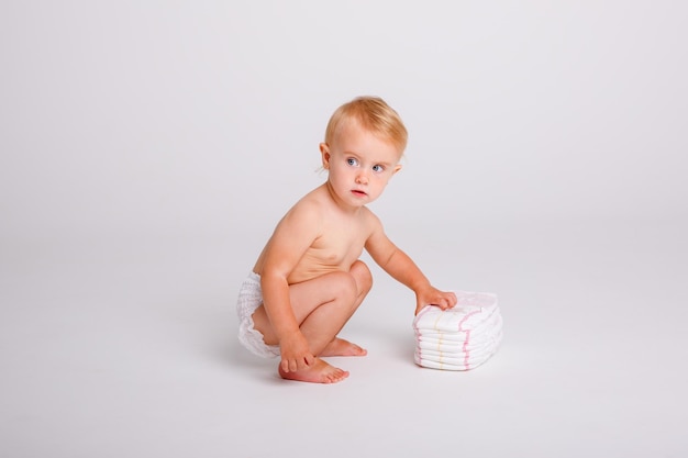 bambina in un pannolino con una pila di pannolini su sfondo bianco