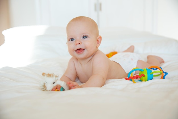Bambina in un pannolino sdraiato sul letto con sonagli di giocattoli
