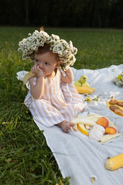 Bambina in un vestito a strisce su un picnic in un parco cittadino.